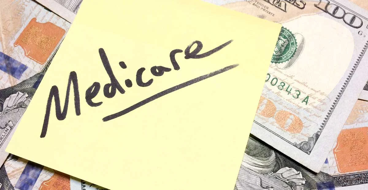 Medicare written on a yellow sticky note laying on top of money.