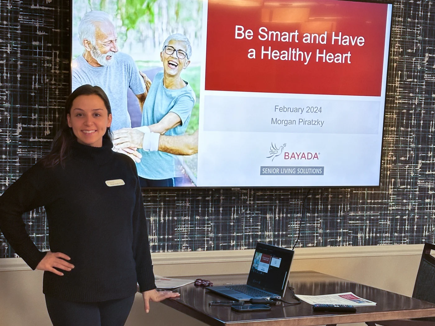 Smiling woman standing in front of health-focused slideshow.