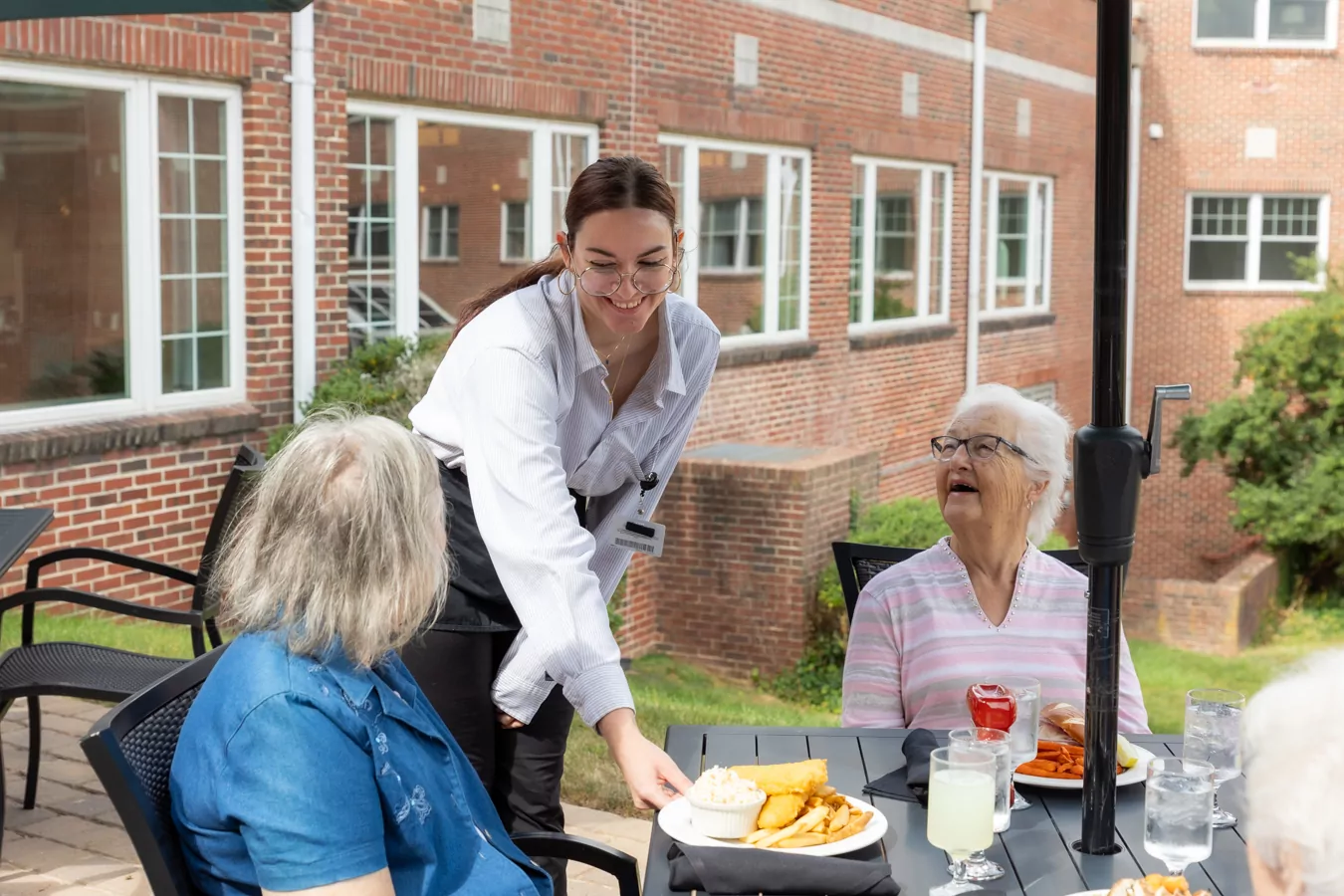 Waitress serving food to residents outdoors