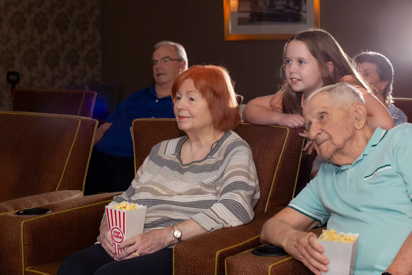 Couple watching a movie with grandchild and other in background