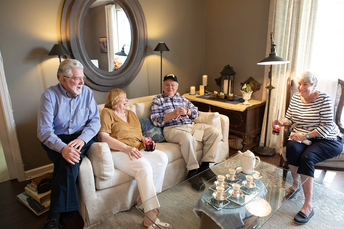 Group of two couples smiling together in apartment.