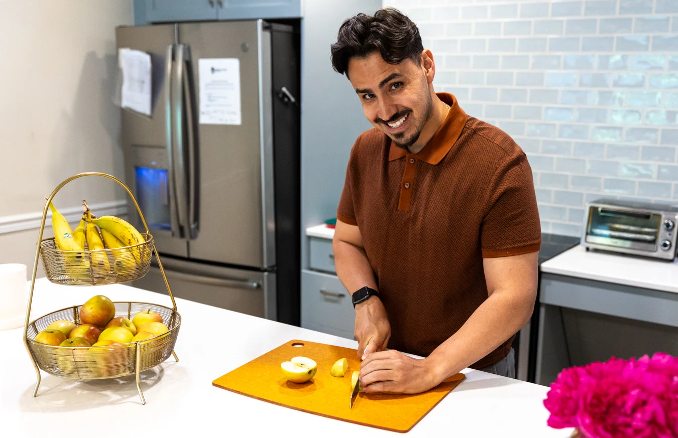Man preparing food. Smiling young man slicing food on a cutting board.