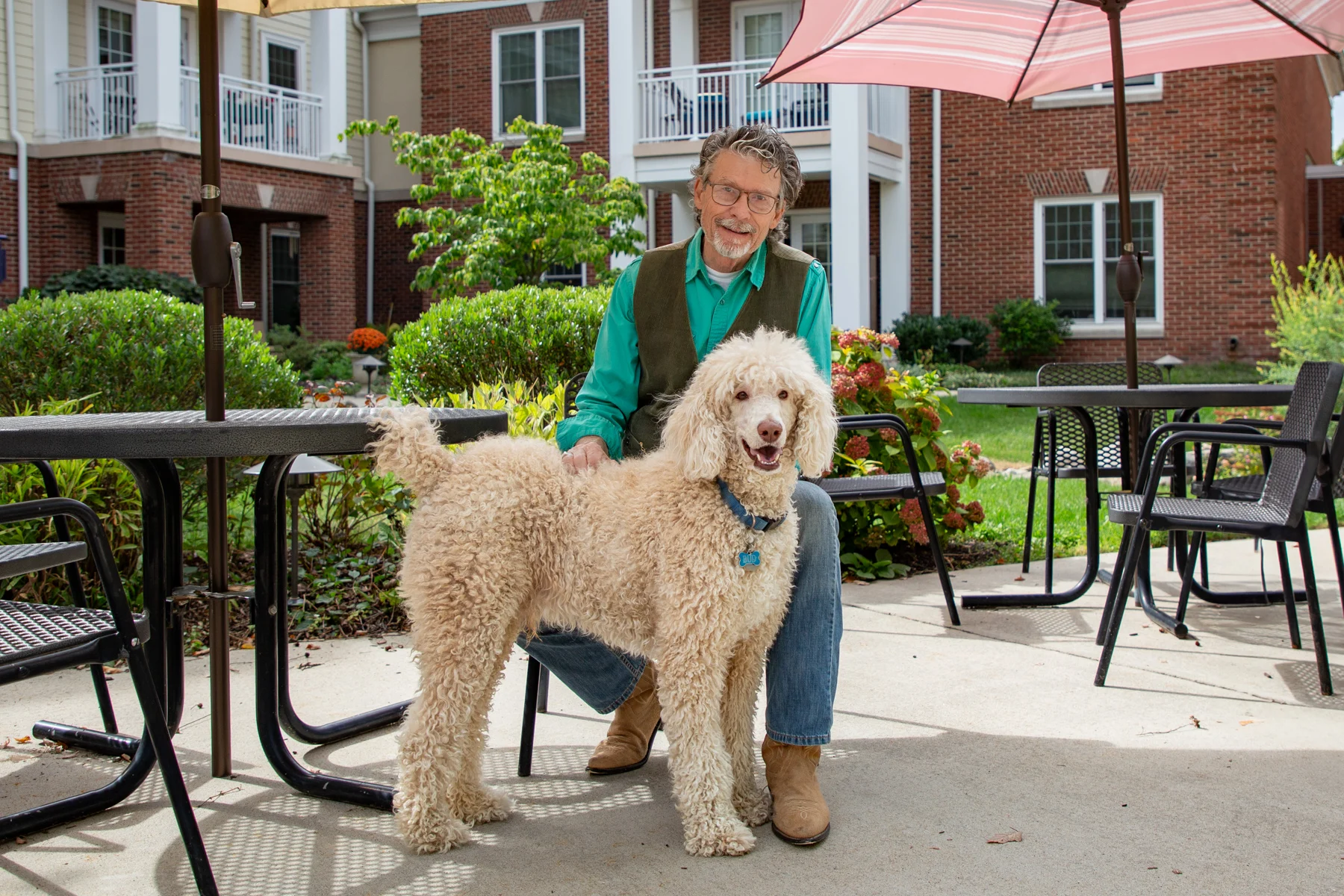 Smiling senior man with his dog outdoors sitting at picnic table.