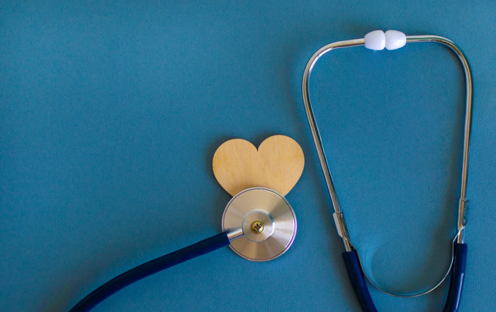 Stethoscope and a wooden heart on a blue background.