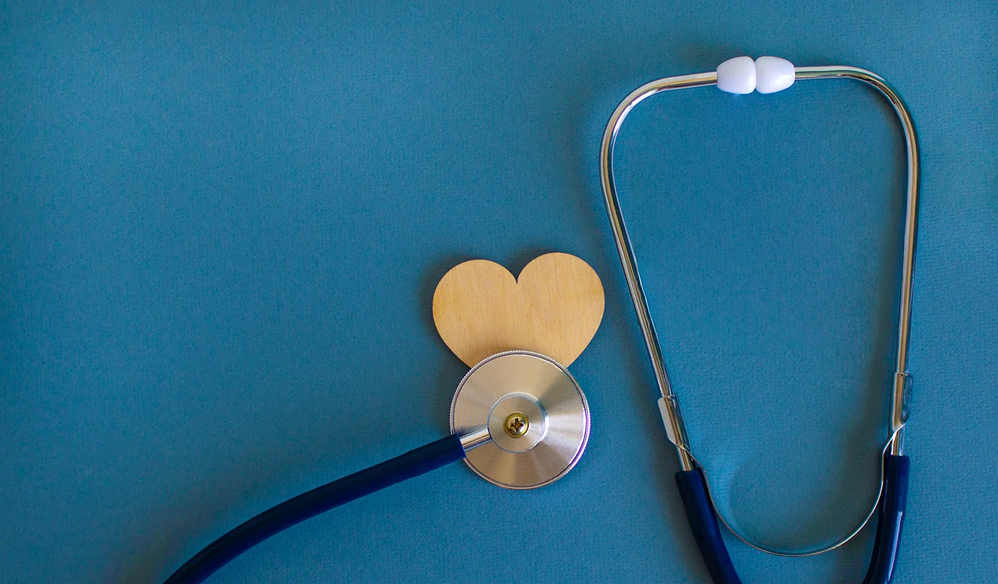 Stethoscope and a wooden heart on a blue background.