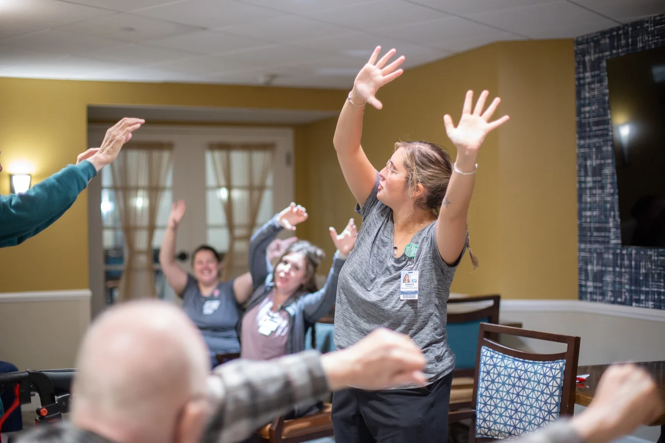Three women at front of a room showing varied exercises to senior audience.