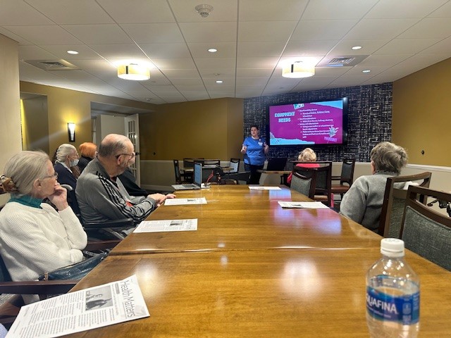 Woman presenting slideshow to seated residents.