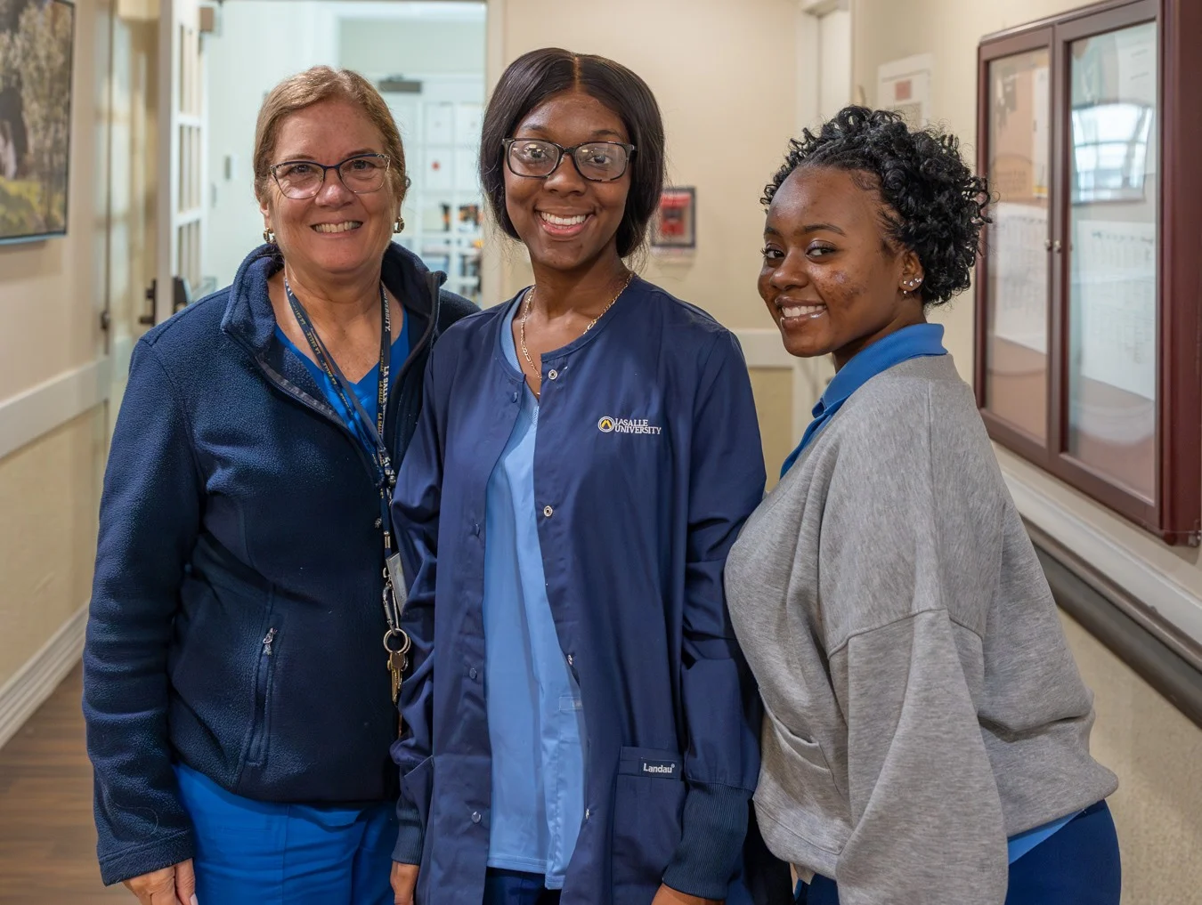 Group of women smiling in nurse's scrubs and jackets.
