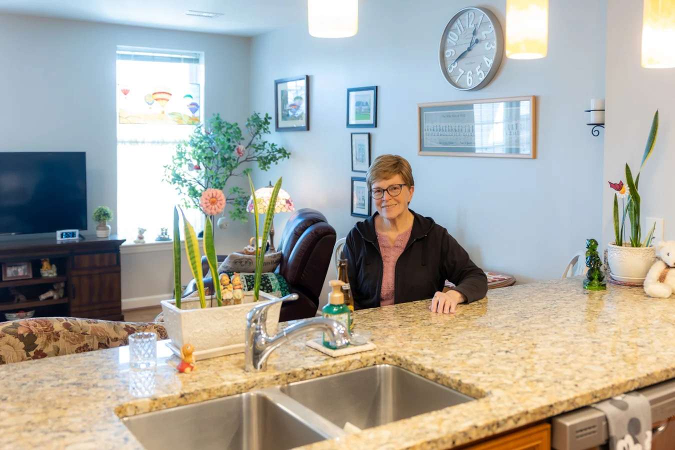 Senior woman in kitchen. Smiling senior woman sitting at her kitchen countertop.