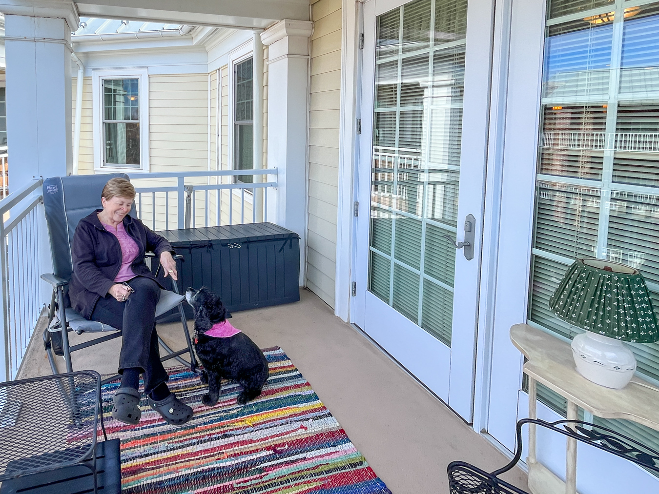 IMG_6730 Smiling senior woman sitting in chair on the patio with her dog.
