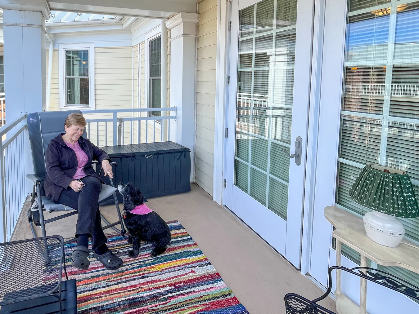 Smiling senior woman sitting in chair on the patio with her dog.