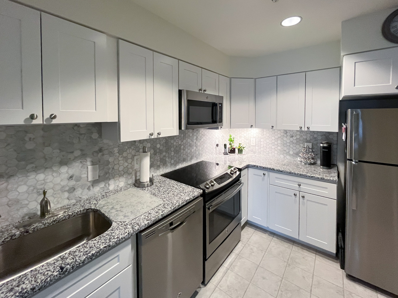 Modern kitchen with white cabinets and stainless steel appliances.