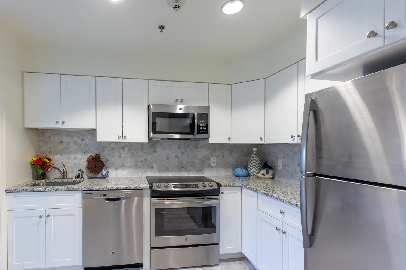 White, well-lit kitchen with stainless steel appliances.