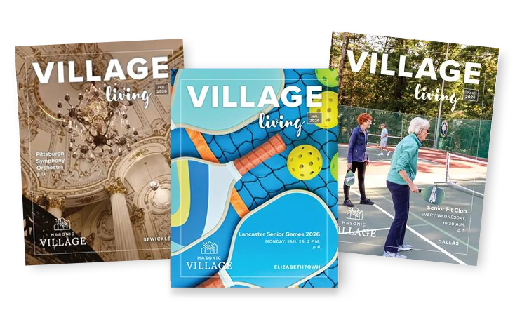 Three Village Magazine issues laid on top of one another.