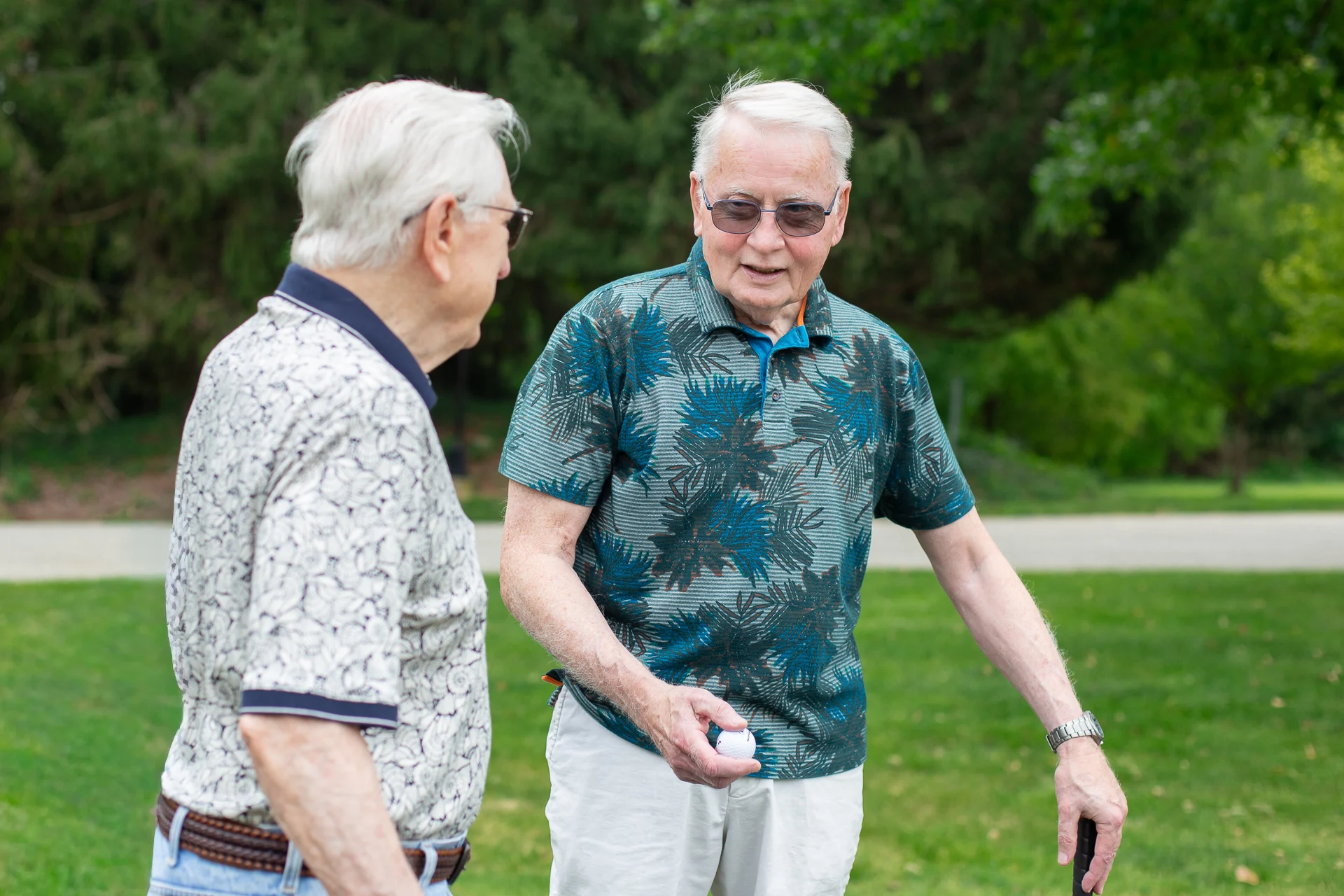 Senior men playing golf. Smiling senior men holding golf clubs while chatting outdoors.
