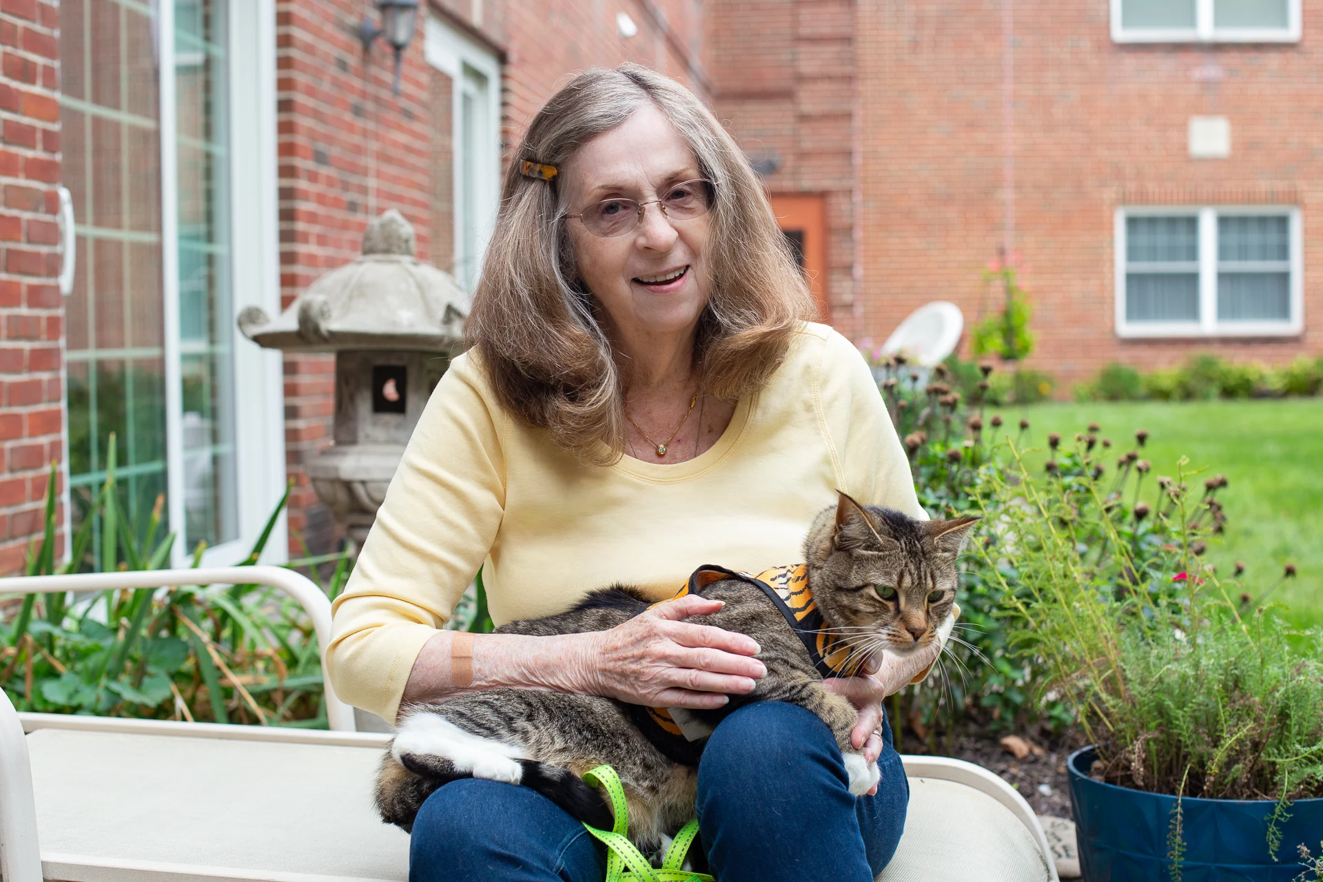 Smiling senior woman seated outdoors while holding her cat.