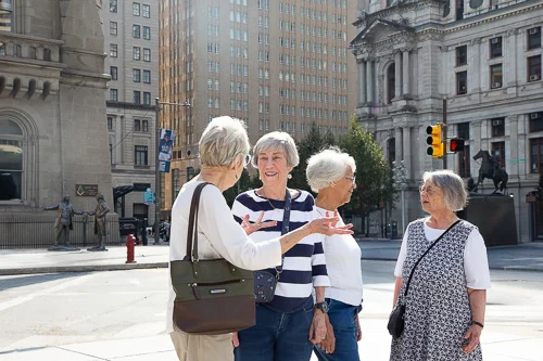 Smiling group of senior women standing together in front of Masonic Temple and Philadelphia City Hall.
