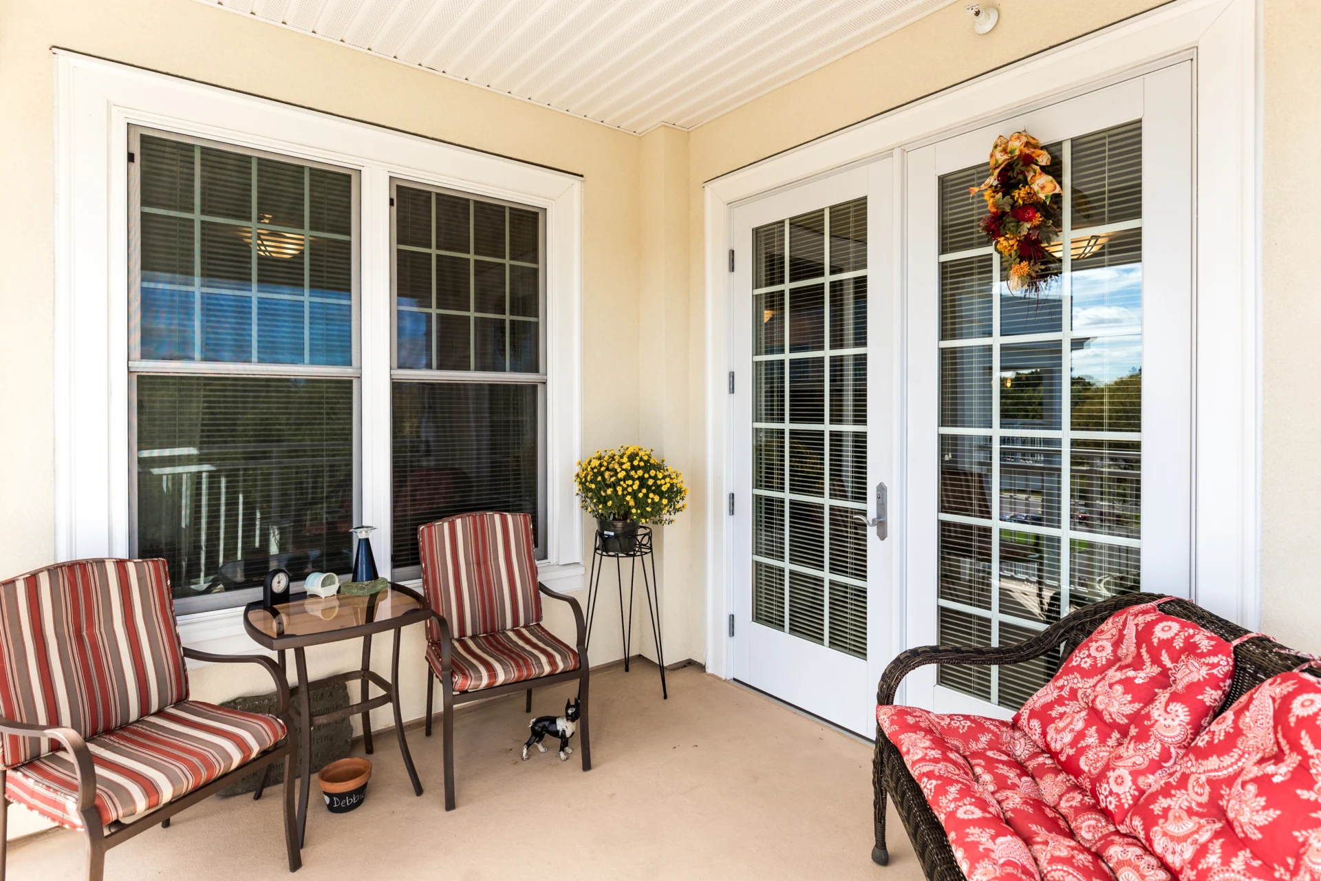Cozy porch with red accented furniture and large, windowed French doors.
